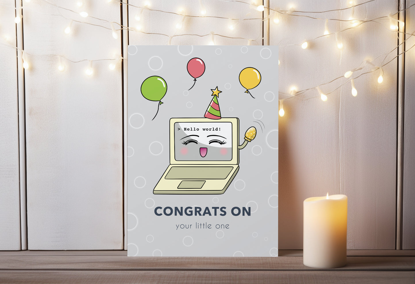 A kawaii greeting card from Rainbow & Bubbles, showing a laptop displaying Hello world! Baby Laptop is celebrating the birth of a baby. The front says "Congrats on your little one".