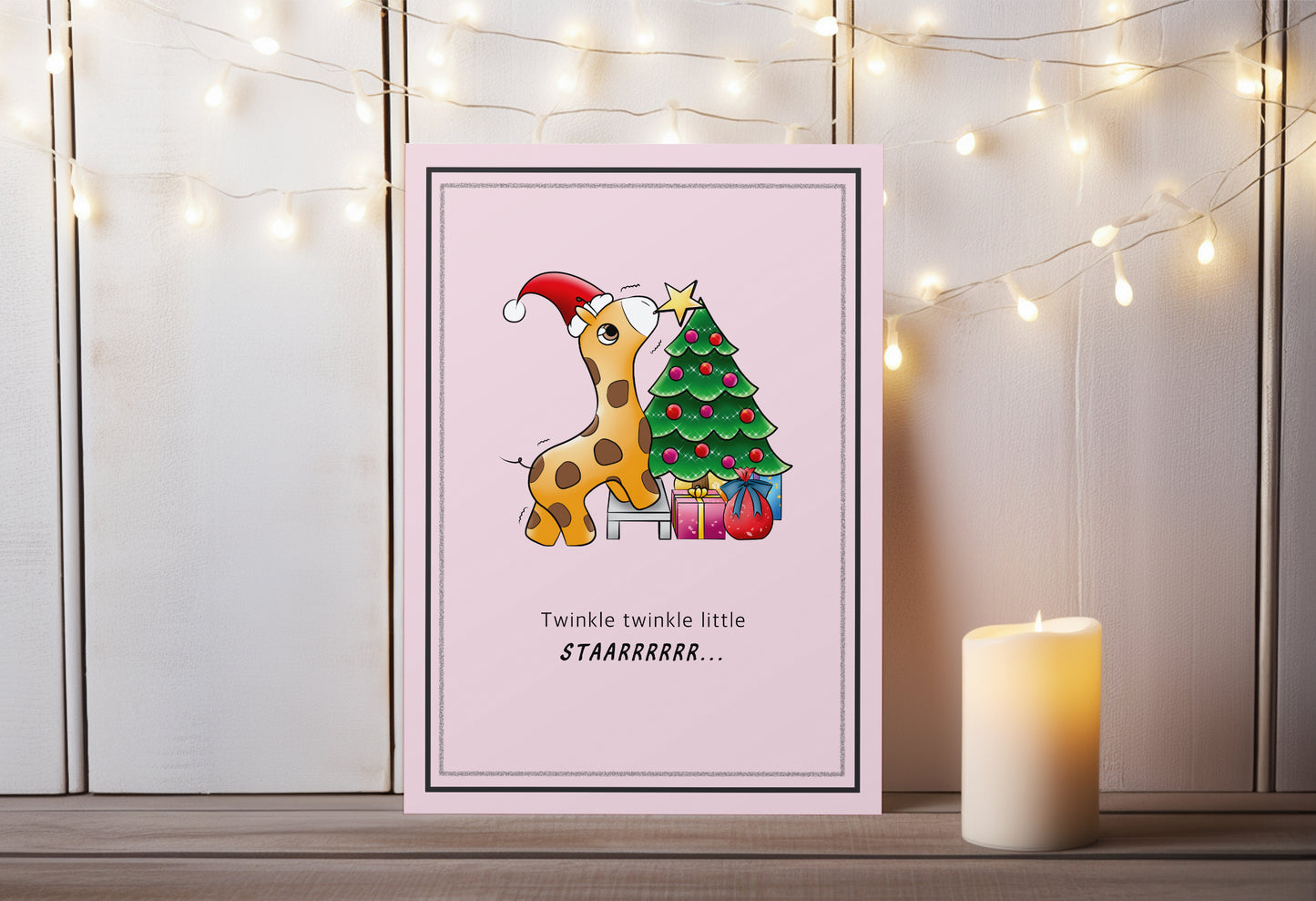 A kawaii greeting card from Rainbow & Bubbles, showing a baby giraffe with. santa hat struggling to put the star on the Christmas tree.