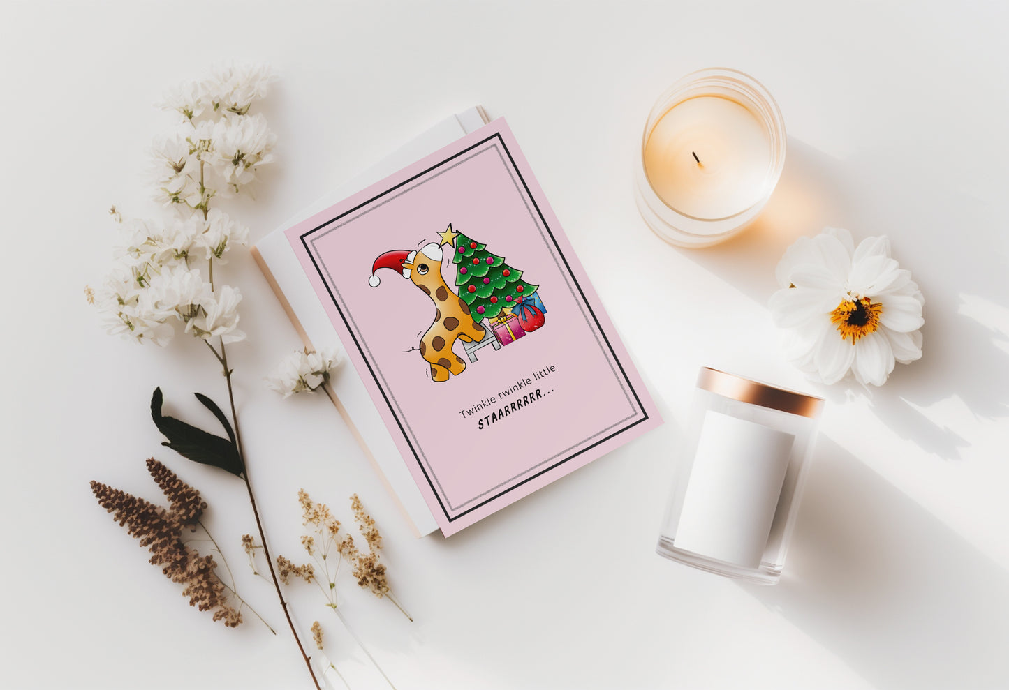 A kawaii greeting card from Rainbow & Bubbles, showing a baby giraffe with. santa hat struggling to put the star on the Christmas tree.