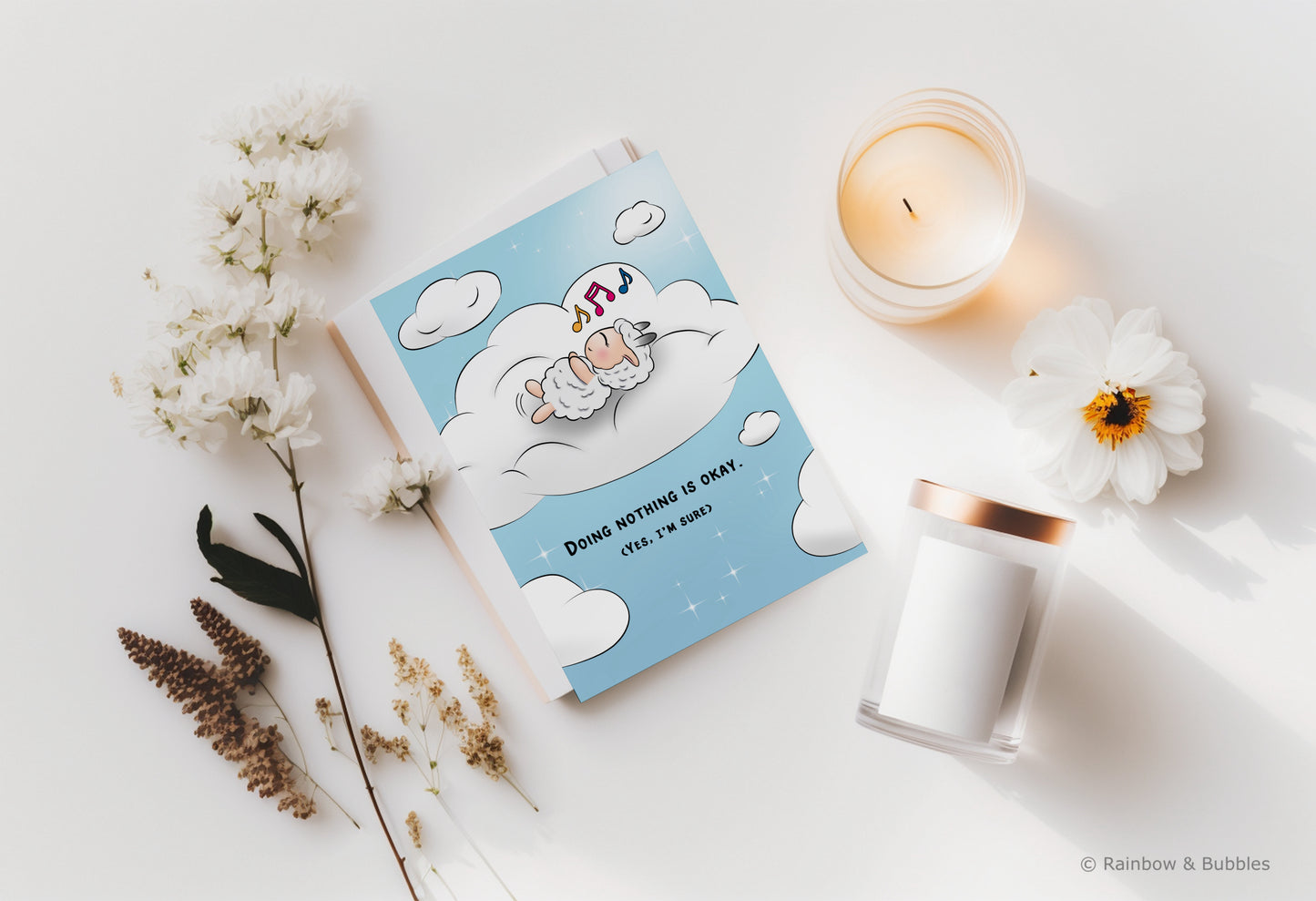 A kawaii greeting card from Rainbow & Bubbles, showing a sheep doing nothing, simply relaxing in a bed of cloud and humming his favorite tune.