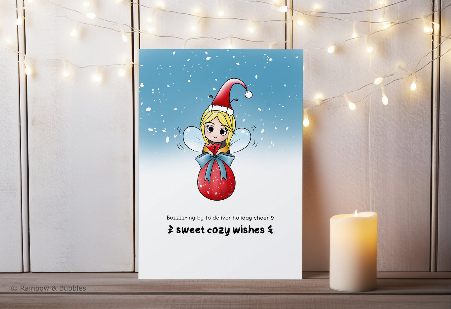 A kawaii greeting card from Rainbow & Bubbles, showing a bee with a santa hat delivering a big pretty bag of gifts.