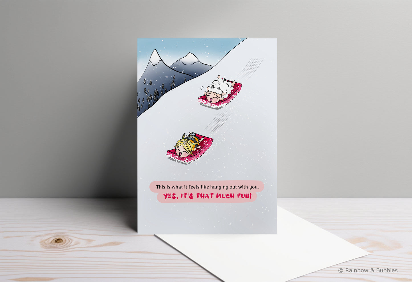 A kawaii greeting card from Rainbow & Bubbles, showing a sheep and a bee having fun snow sledding.