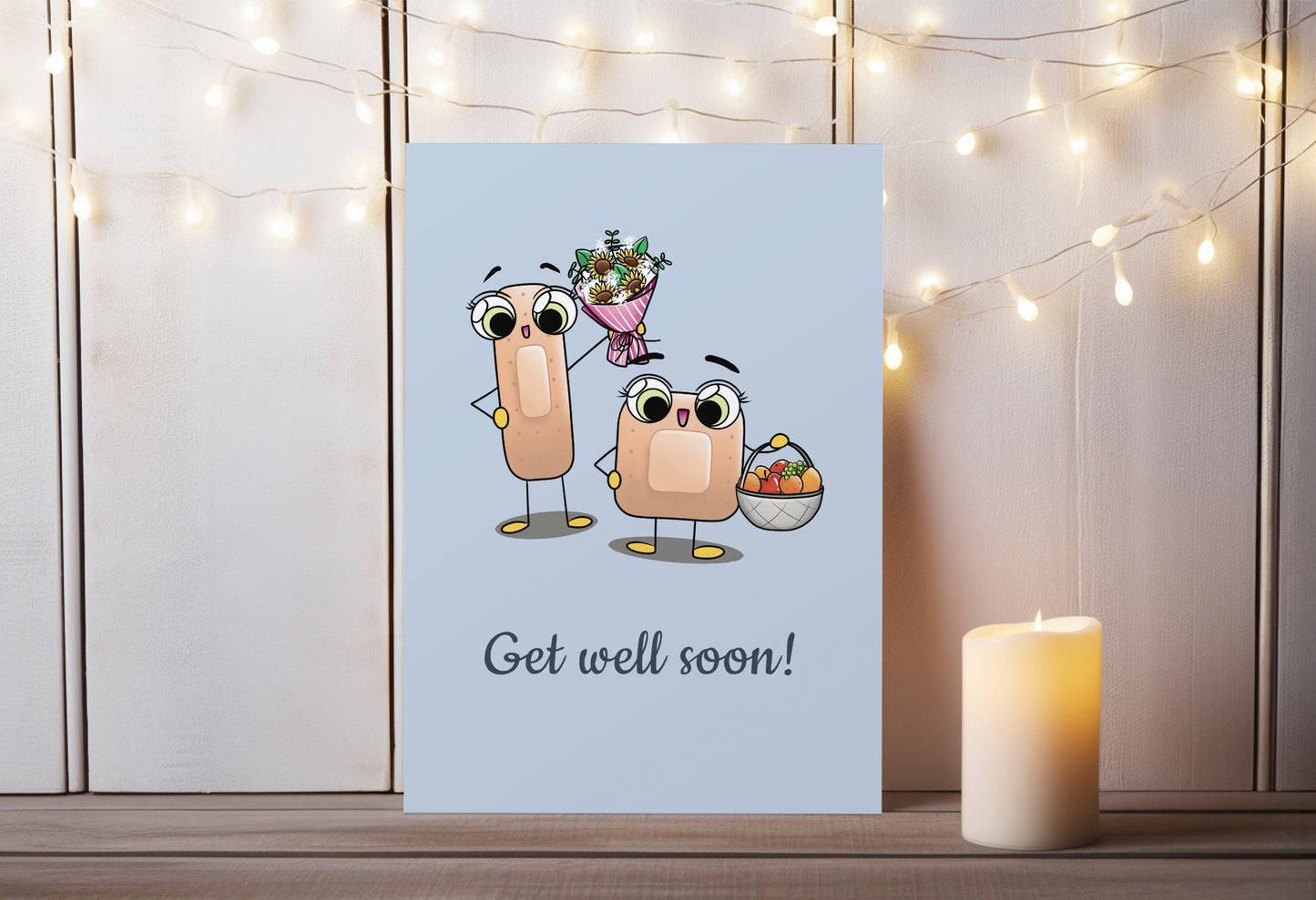 A kawaii greeting card from Rainbow & Bubbles, showing two kawaii bandages holding a flower bouquet and a fruit basket, with the text Get Well Soon.