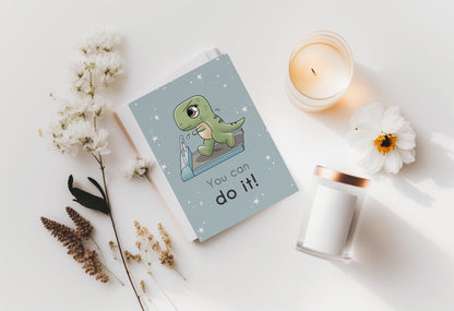 A kawaii greeting card from Rainbow & Bubbles, showing a t-rex running and sweating on the treadmill. The front says "You can do it!"