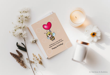 A kawaii birthday card from Rainbow & Bubbles, showing a bee holding a heart balloon.